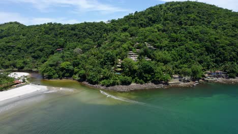 Aerial-view-following-a-boat-driving-in-to-the-Sahy-river-in-Barra-Do-Sahy,-Brazil
