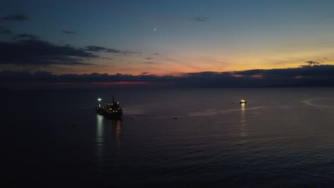 Aerial-of-boat,-oil-tanker-at-dusk,-parked-in-the-ocean,-unloading