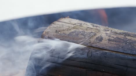 Close-up-of-a-log-of-wood-burning-while-smoke-is-coming-out-of-a-crevice