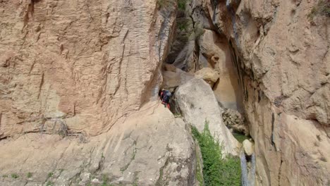 Climber-ascending-a-vertical-rock-wall-next-to-a-waterfall