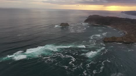 Pacific-coastline-of-Costa-Rica-at-sunset-with-rocky-point,-Aerial-flyover-shot