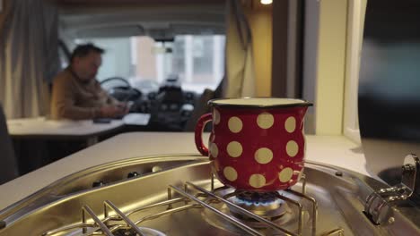 Burning-gas-stove-or-cooker-in-campervan-and-man-sitting-inside,-closeup-view