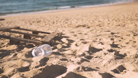 Botella-De-Agua-De-Plástico-Desechada-En-Una-Playa-De-Arena