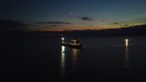 Aerial-approaching-boat,-oil-tanker-in-sea-at-dusk,-night-view