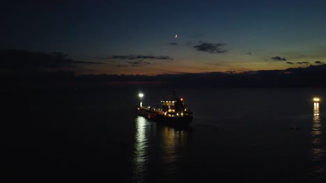Aerial-view-of-boat,-oil-tanker-in-the-ocean-at-dusk,-night-view