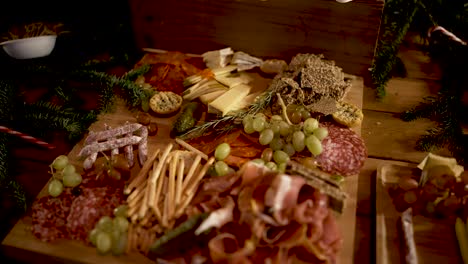 Assorted-cured-meats,-grapes-breadsticks-and-prosciutto-appetizer-on-cutting-board-with-rosemary-herbs,-Orbit-around-shot