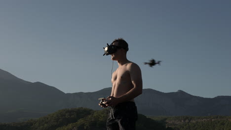 Drone-Fpv-Volando-Por-Tu-Hombre-Con-Gafas-Y-Control-Remoto-Con-Colinas-De-Montaña-En-El-Fondo