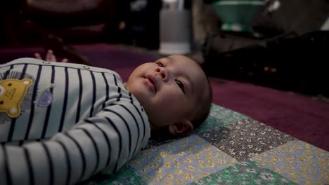 Cute-4-Month-Old-Indian-Baby-Boy-Laying-On-Mat-On-The-Floor-,-Wriggling-And-Gesturing