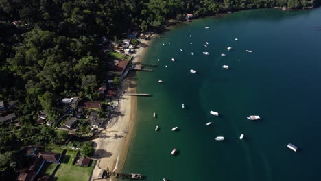Aerial-view-of-boats,-moored-at-a-beach-in-Ilha-Grande,-sunny-Brazil---tilt,-drone-shot