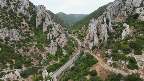 Sharp-pointed-rocks-reveal-road-to-mainland-of-Sardinia,-Italy---4k-Aerial-Dolly-Forward