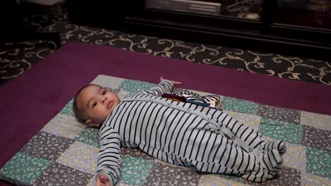 Entzückender-4-Monate-Alter-Indischer-Junge,-Der-Auf-Einer-Matte-Auf-Dem-Boden-Liegt,-Zappelt-Und-Gestikuliert