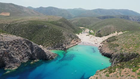 Cala-Domestica-Beach,-Blue-Cove-and-Green-Mountains-in-Sardinia,-Italy---4k-Aerial