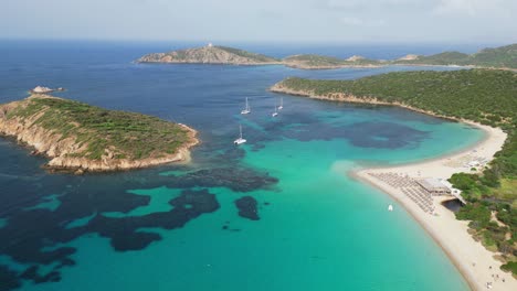 Turquoise-blue-bay,-Tuerredda-beach,-boats-and-islands-in-Teulada,-Sardinia,-Italy---4k-Aerial