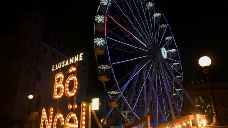 Lausanne,-Vaud-Canton,-Switzerland---20-December,-2022:-Ferries-wheel-rotating-at-night-with-lights-at-amusement-park