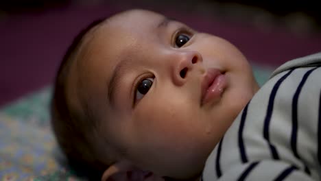Entzückender-4-Monate-Alter-Indischer-Junge,-Der-Mit-Weit-Aufgerissenen-Augen-Lächelt-Und-Auf-Einer-Decke-Auf-Dem-Boden-Liegt