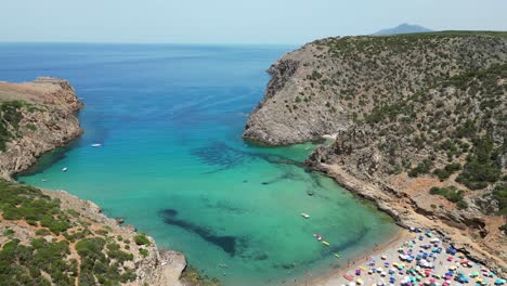 Tourists-Swim-and-Relax-at-Cala-Domestica-Beach-in-Buggerru,-Sardinia,-Italy---4k-Aerial