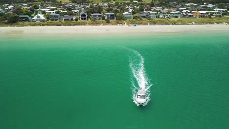 Aerial-view-of-fishing-boat-leaving-the-beach-heading-out-to-sea