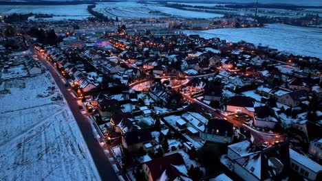 Beautiful-aerial-drone-shot-over-rows-of-houses-and-roads-covered-with-snow-over-on-a-cold-winter-evening