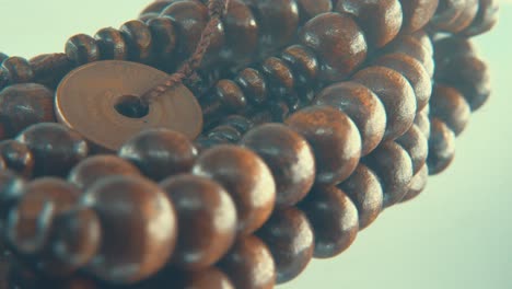 Macro-rotating-shot-of-a-wooden-round-beads-necklace-with-coin-medallion