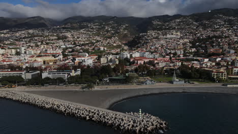 Toma-Aérea-Sobre-La-Playa-Del-Puerto-De-Funchal-Y-Sobre-Las-Casas-Y-Edificios-Cerca-De-La-Costa