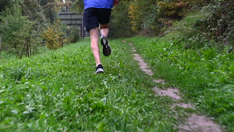 low-to-the-ground-shot:-an-endurance-athlete-runs-fast-on-a-dirt-path-and-grass