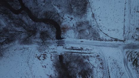 Top-Down-Aufnahme-über-Schneebedeckten-Pfad-über-Einen-Schmalen-Fluss-An-Einem-Kalten-Wintertag