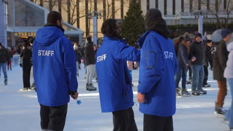 Eislaufpersonal-In-Blauen-Uniformen-Und-Schlittschuhläufer-Auf-Der-Eisbahn-Im-Winter-In-New-York,-Usa
