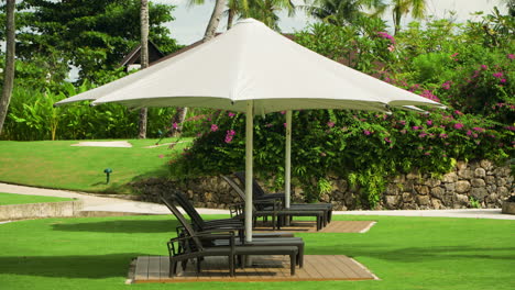 Sun-umbrellas,-lounge-chairs-in-tropical-garden,-Shangri-la,-Cebu,-Philippines