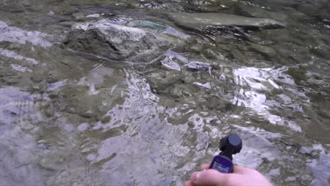 a-filmmaker-holds-an-action-cam-in-his-hands-and-captures-footage-of-water-from-a-swiss-river