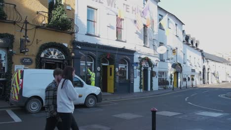 County-council-worker-fixing-lamp-post-after-accident-and-couple-walking-on-a-sunny-winter-day-in-Kinsale,-Ireland