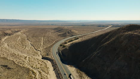 Typischer-Kalifornischer-Verkehr-Auf-Dem-Highway-58,-Der-Sich-Durch-Rote-Felsschluchten-In-Der-Mojave-Wüste-Schlängelt---Luftaufnahme