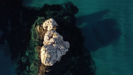 Rotating-aerial-drone-shot-of-a-rock-formation-in-water