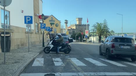 Man-with-white-helmet-Sitting-On-A-Motorbike-And-Talking-On-Phone-On-The-Street-Of-Garret-on-Estoril,-Cascais
