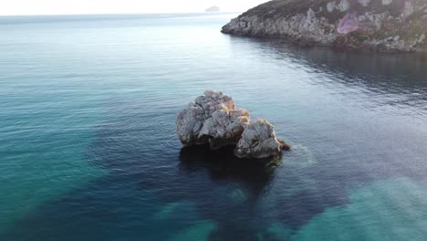 Aerial-view-of-offshore-white-rock-formation-in-turquoise-water,-secluded-bay
