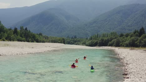 Aerial-shot-of-four-people-kayaking-emerald-green-alpine-Soca-River