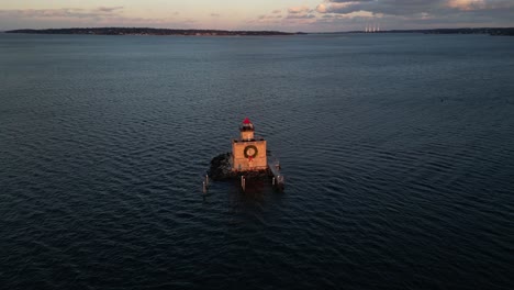An-aerial-view-of-the-Huntington-Harbor-Lighthouse-on-Long-Island,-NY-at-sunset,-with-a-Christmas-wreath