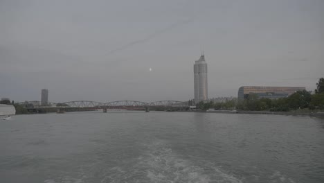 Schifffahrt-Entlang-Der-Donau-In-Wien-Mit-Dem-Jahrtausendturm-Im-Hintergrund-Am-Abend