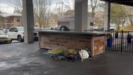 Homeless-Person-Sleeping-On-The-Floor-In-A-Covered-Food-Stall-Area-In-Ashland,-Oregon,-USA