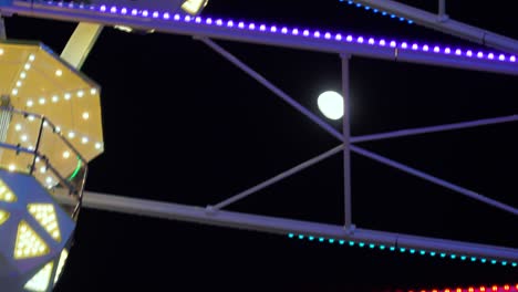Ferris-Wheel-Attraction-Spinning-with-Moon-in-the-Background,-Evening,-Night,-Close-Up