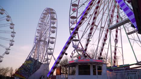 Multiple-Ferris-Wheels-Spinning-at-Manufacturer-of-Fairground-Attractions,-Dusk