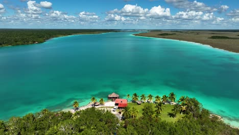 Aerial-view-in-front-of-a-exotic-resort-at-the-laguna-Bacalar,-in-Mexico---descending,-drone-shot
