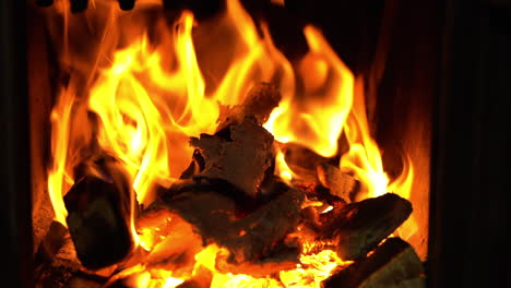 Ember-and-firewood-in-flames-in-stove,-static-closeup-view-on-yellow-blaze