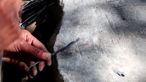 Close-up-of-African-man-shaping-piece-of-metal-with-a-hammer-to-create-an-arrowhead