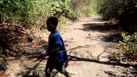 Hadzabe-tribesman-boy-cutting-a-branch-with-a-knife-to-make-arrows-and-other-weapons-in-slow-motion