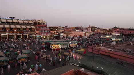 Morocco,-Marrakesh,-timelapse-during-sunset-and-at-night-from-the-middle-of-the-beautifully-lit-city-centre-and-shopping-people