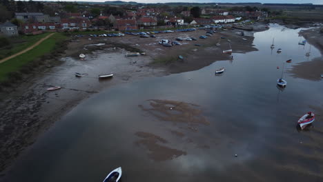 Aerial-Drone-Shot-Flying-Over-Creek-at-Low-Tide-with-Sailing-Boats-and-Boathouse-in-Burnham-Overy-Staithe-North-Norfolk-on-Cloudy-Gloomy-Moody-Day-UK