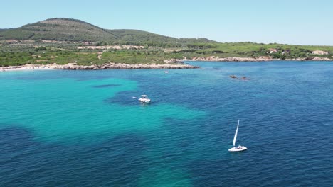 Solo-Sailor-sails-along-Cala-Spinosa-Beach-in-Sardinia,-Italy---4k-Aerial
