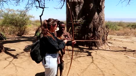 Afrikanischer-Hadzabe-stammmann,-Der-Einer-Touristenfrau-Beibringt,-Wie-Man-Mit-Pfeil-Und-Bogen-Jagt