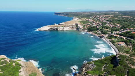 S'-Archittu-beach-town-and-blue-bay-at-west-coast-of-Sardinia,-Italy---4k-Aerial