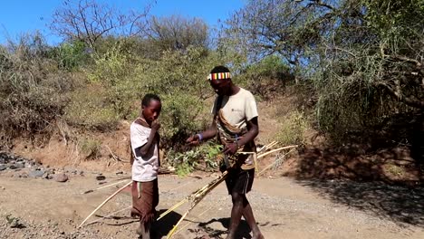 Tribu-Hadzabe-Local-Hombre-Y-Niño-Comiendo-Bayas-De-Una-Rama-De-árbol-En-La-Sabana-Africana